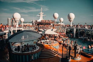 Many travelers gathered around enjoying and relaxing on the open deck on a cruise