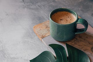 teal coffee cup with coffee on a stone table