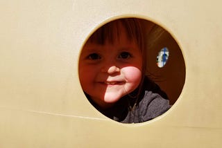 Paige looking out of a playground spy hole