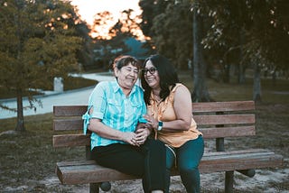 Two women laughing on a park bench.