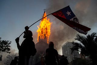 Igreja de Assunção sendo incendiada no Chile e manifestantes comemorando.