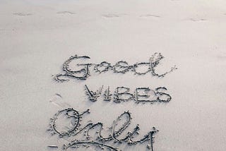 on the beach written in sand, “Good Vibes Only”