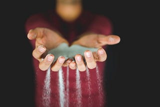 An image of hands holding sand that trickles down, metaphor for time slipping away