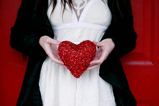 Close up of the torso and hands of a woman holding a big fluffy heart