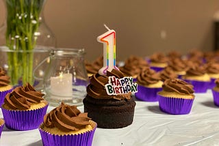 A table of birthday cupcakes, one of which has a ‘1’ candle and ‘Happy birthday’ decoration