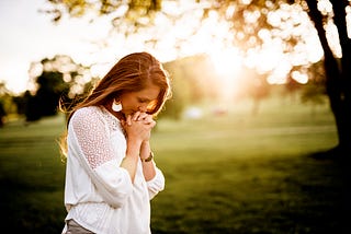 Woman with hands clasped, bowing head in prayer