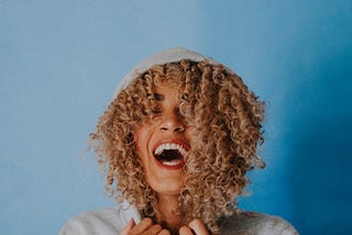 laughing, happy woman with curly hair and a hoodie