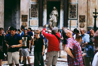 A group of people in an art gallery looking up and taking pictures