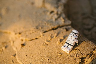 Lego storm trooper sitting in the sand while contemplating life.