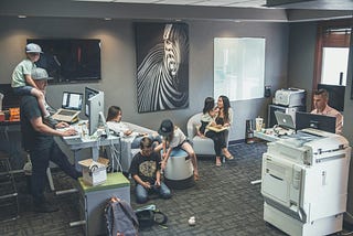 Two men and a women working in an office space alongside several kids