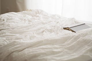 crumpled bedsheets and an open book