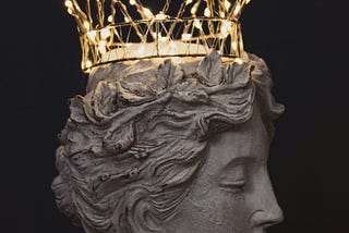 A Roman bust wearing a crown made of wire and lights.