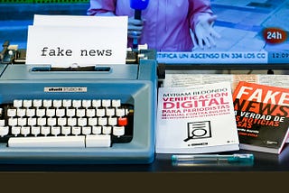 A typewriter and books teaching how to create fake news for digital media
