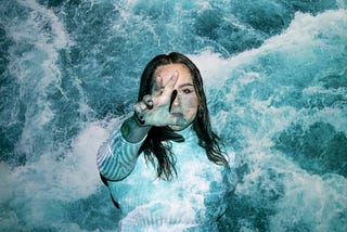 Woman in water reaching for a helping hand.