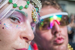 zoomed into faces of two glitter filled faces with colorful acessories