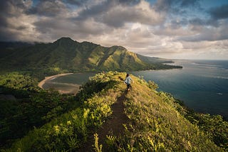 A person running on a hilly landscape trail close to the ocean