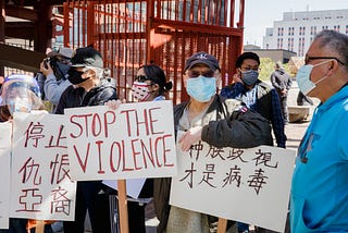 Asian-American protesters hold up signs in Chinese and English saying “STOP THE VIOLENCE”