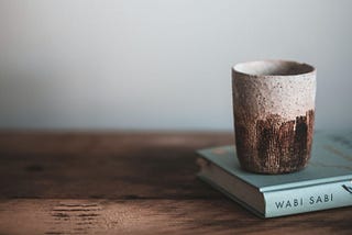 Wabi Sabi book with natural material cup on wooden bench