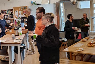 Two photos showing groups of adults standing around an office kitchen chatting and eating pastries