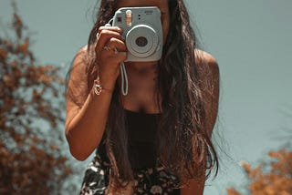 A woman holding a camera to her face, taking a photo.