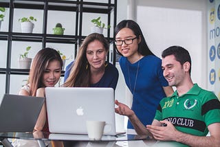 Four people huddled around a laptop