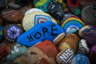 A pile of brightly painted stones. One has the word hope on it.