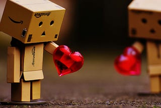Little box person holding a red plastic toy gem heart