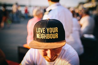 Man wearing a baseball cap with the words “love your neighbour” on it
