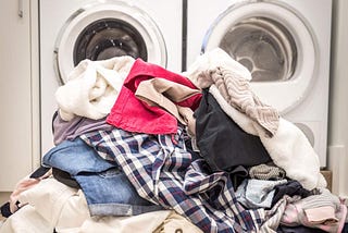 Pile of clothing outside washer/dryer ©Mariakray