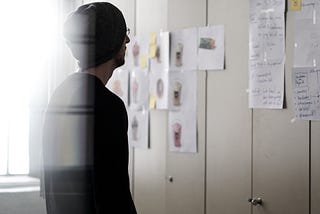 A man is reading notes on the wall.