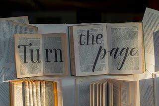 Open books; pages yellowed. The words ‘Turn the page’ superimposed.