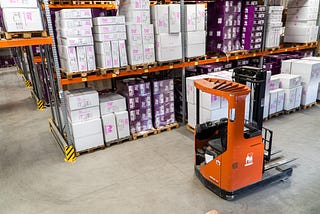 A picture of a parts picker in a warehouse near pallet racking.