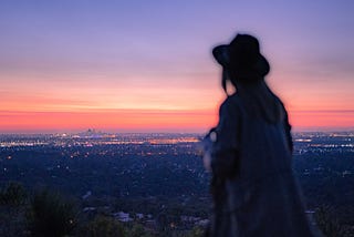 Man with a hat watching the city lights from afar