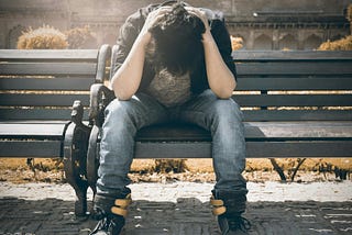 A man sitting on a bench with his head down