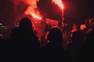 A crowd holding red flares