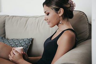 women sitting on the couch relaxing, drinking a mug of tea or coffee