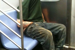 This is an image of a man with his shirt pulled up over his face to give him privacy while his hand is in his pants in this public location. His butt cheeks are absolutely touching the seat. There is sweat there. Between his butt cheeks.