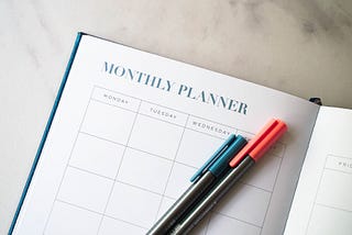 A monthly planner with a blue pen and a red pen on top of the page