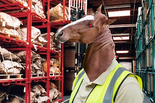 A horse-headed “reverse-centaur” whose eye has been replaced by the glowing eye of HAL9000 from 2001: A Space Odyssey. They are wearing a hi-viz vest and posed in shelving-aisles of an industrial warehouse.