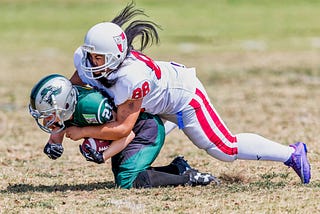 Photo of a football player tackling another football player from behind.