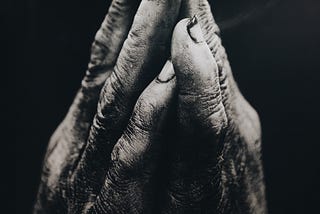 a black and white photo of hands together in prayer