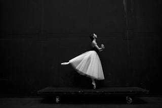 Black and white image of ballerina with low arabasque extension.