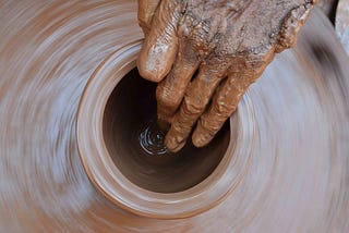 a craftsman moulding a container made from clay