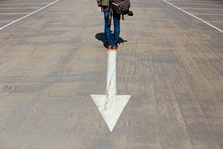 Person standing in front of an arrow pointing backwards