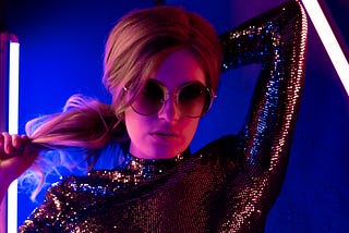 A young woman in a sparkly evening top with big sun glasses