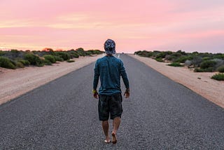 person walking alone down an empty road