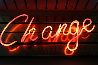Red neon sign with the word Change written in cursive.