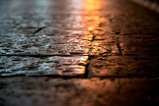 A macro photograph of a cobblestone street in the night light.
