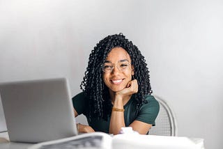 smiling woman sitting at table with laptop