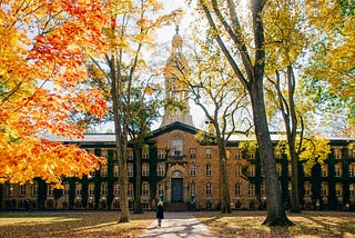 A campus building in the background, autumnal trees in foreground